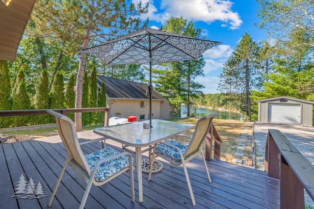 6122 Beach Rd, Johannesburg, MI 49751 - wooden terrace featuring a storage unit, outdoor dining space, a water view, and an outbuilding