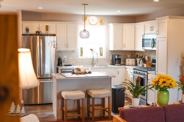 3211 Jenson St, Lewiston, MI 49756 - kitchen with white cabinetry, stainless steel appliances, backsplash, a kitchen island, and a sink