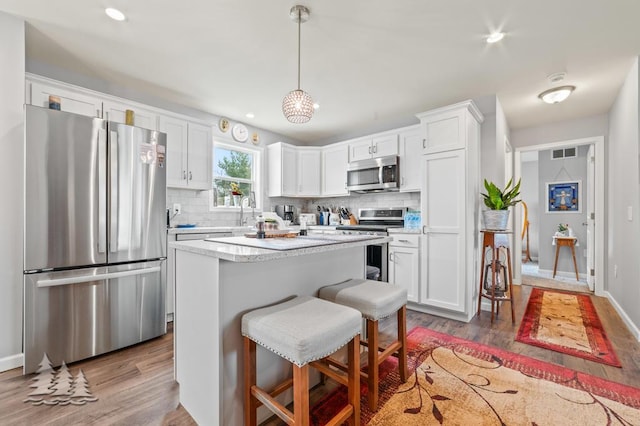 3211 Jenson St, Lewiston, MI 49756 - kitchen featuring visible vents, appliances with stainless steel finishes, dark wood-type flooring, white cabinetry, and backsplash