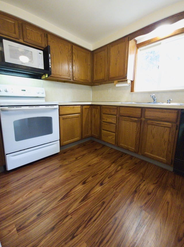 638 Old Trail Dr, Houghton Lake, MI 48629 - kitchen with white appliances, brown cabinetry, light countertops, and dark wood-style flooring