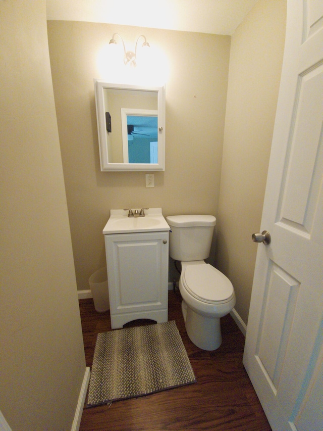 638 Old Trail Dr, Houghton Lake, MI 48629 - bathroom featuring vanity, baseboards, wood finished floors, and toilet