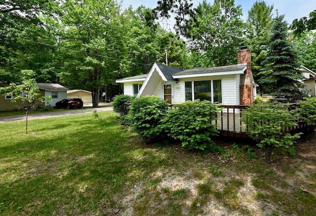 638 Old Trail Dr, Houghton Lake, MI 48629 - view of side of property with a chimney, a lawn, and a garage