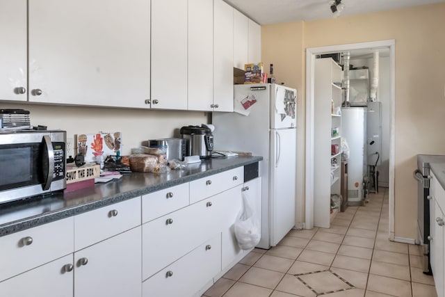 2007 M30, Gladwin, MI 48624 - kitchen with stainless steel microwave, freestanding refrigerator, light tile patterned flooring, white cabinetry, and dark countertops