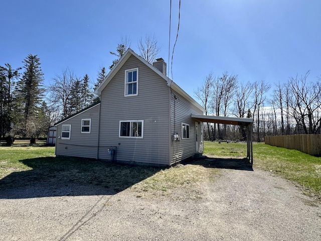 1117 Mackinaw Ave, Cheboygan, MI 49721 - view of home's exterior featuring fence, driveway, a chimney, a yard, and a carport