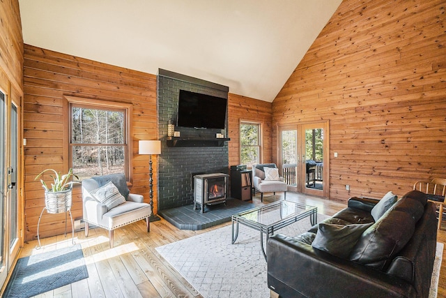 living area featuring wood-type flooring, a wood stove, wood walls, and high vaulted ceiling