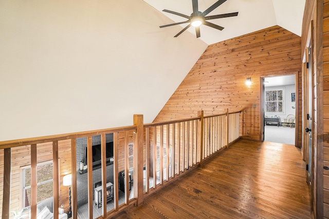corridor featuring hardwood / wood-style flooring, wood walls, and high vaulted ceiling