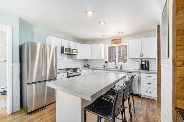 kitchen with backsplash, a kitchen bar, stainless steel appliances, and a sink