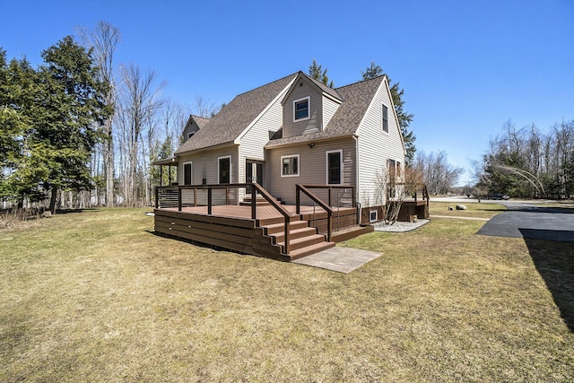 rear view of property with a wooden deck, a lawn, and roof with shingles