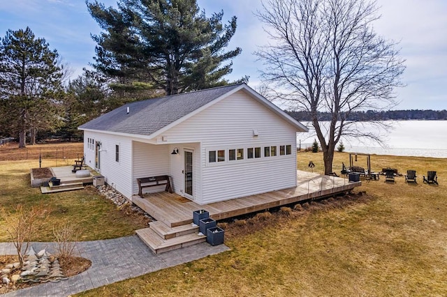 4565 Grant Dr, Lewiston, MI 49756 - view of front of property with a shingled roof, a front lawn, and a deck with water view