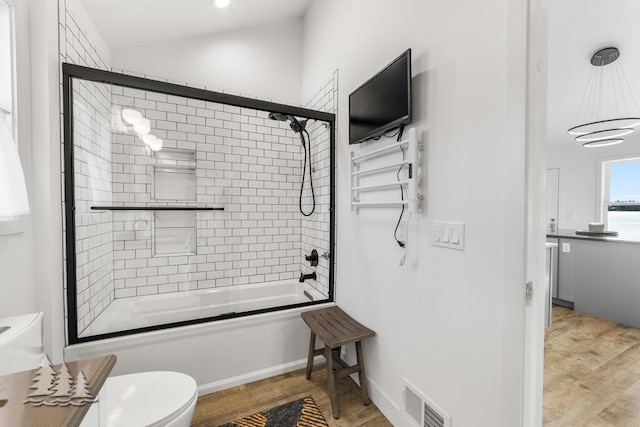 4565 Grant Dr, Lewiston, MI 49756 - bathroom with wood finished floors, visible vents, toilet, and bath / shower combo with glass door