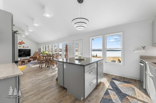 4565 Grant Dr, Lewiston, MI 49756 - kitchen with stainless steel dishwasher, light wood-type flooring, vaulted ceiling, gray cabinetry, and decorative light fixtures
