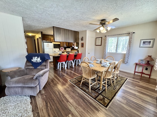 1570 E College Dr, Lewiston, MI 49756 - dining area with dark wood-style floors, a ceiling fan, a textured ceiling, baseboards, and wood walls