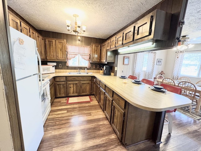 1570 E College Dr, Lewiston, MI 49756 - kitchen featuring white appliances, a textured ceiling, a peninsula, a chandelier, and a breakfast bar