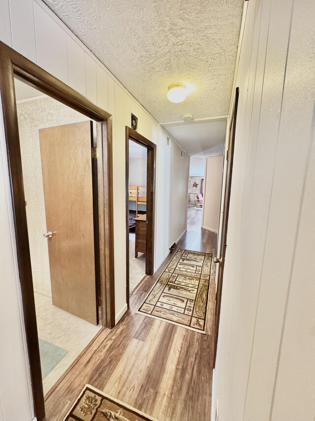 1570 E College Dr, Lewiston, MI 49756 - corridor featuring wood finished floors, a textured ceiling, and wooden walls