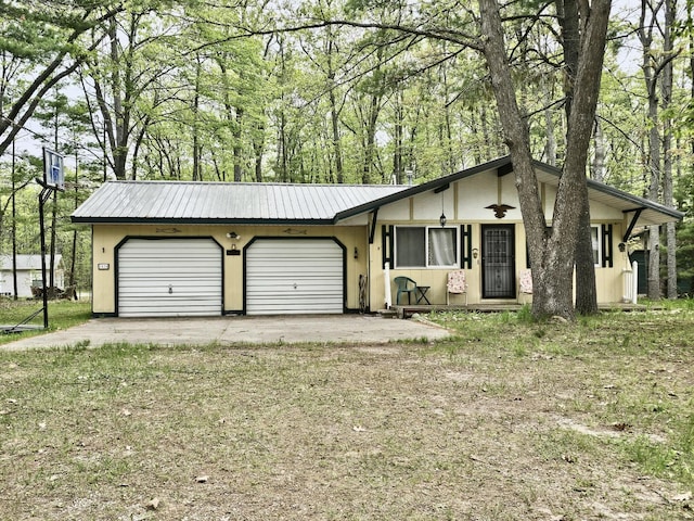 1570 E College Dr, Lewiston, MI 49756 - view of front of house with an attached garage, metal roof, and driveway