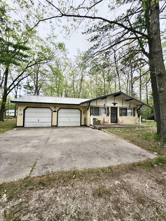 1570 E College Dr, Lewiston, MI 49756 - view of front of property featuring driveway, metal roof, an attached garage, and stucco siding