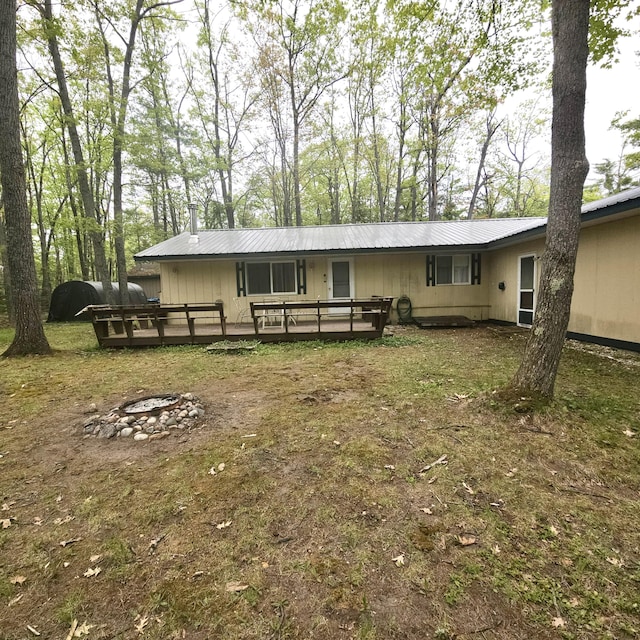1570 E College Dr, Lewiston, MI 49756 - back of house featuring a fire pit, a wooden deck, metal roof, and a yard