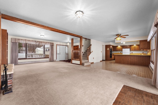 1384 W Higgins Lake Dr, Roscommon, MI 48653 - unfurnished living room featuring stairs, carpet flooring, a sink, ceiling fan, and a baseboard radiator