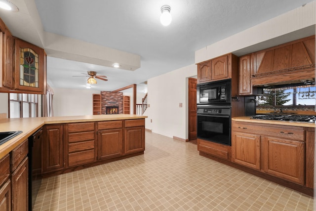 1384 W Higgins Lake Dr, Roscommon, MI 48653 - kitchen with black appliances, light countertops, a ceiling fan, light flooring, and a brick fireplace