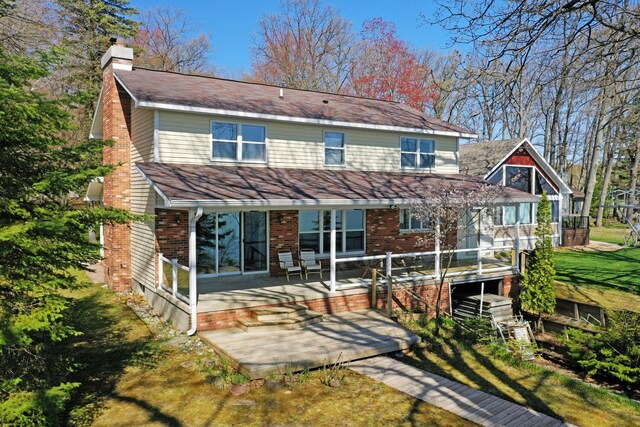 1384 W Higgins Lake Dr, Roscommon, MI 48653 - rear view of house featuring a chimney, brick siding, and a porch