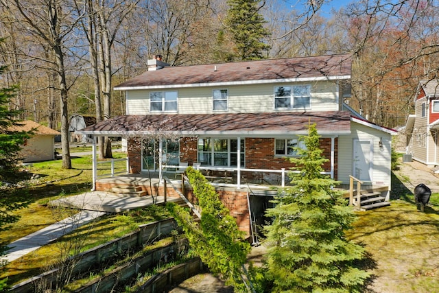 1384 W Higgins Lake Dr, Roscommon, MI 48653 - back of house featuring a porch, a chimney, brick siding, and fence