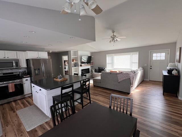 kitchen with open floor plan, dark countertops, a ceiling fan, white cabinetry, and stainless steel appliances