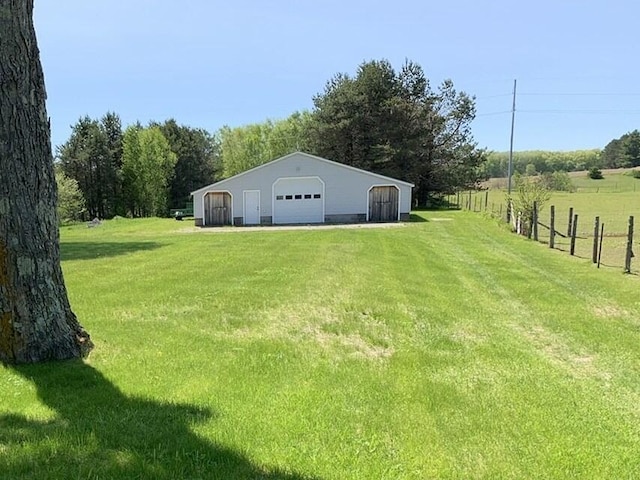 view of yard with an outbuilding, a detached garage, a pole building, and fence