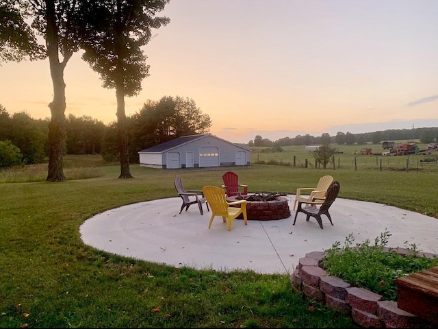 view of patio with an outbuilding, a detached garage, and a fire pit