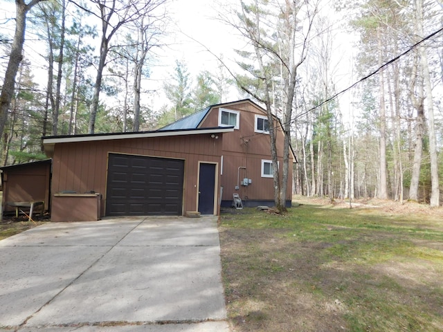 view of side of home featuring concrete driveway, an attached garage, and a gambrel roof