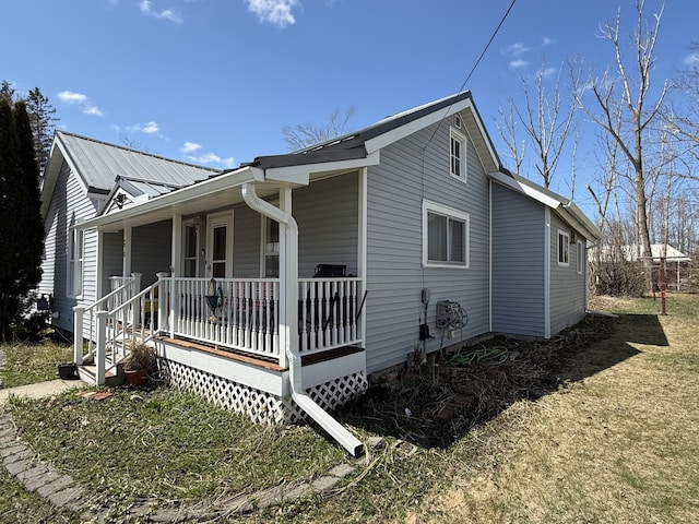 view of side of home featuring a porch, metal roof, and a lawn