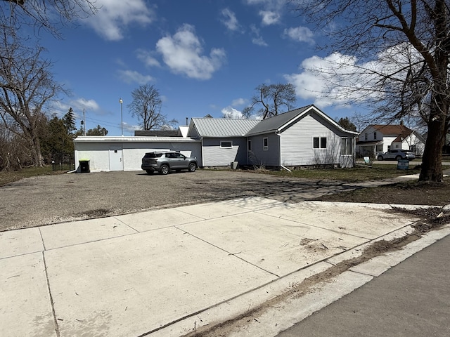 view of property exterior with driveway, metal roof, and an attached garage