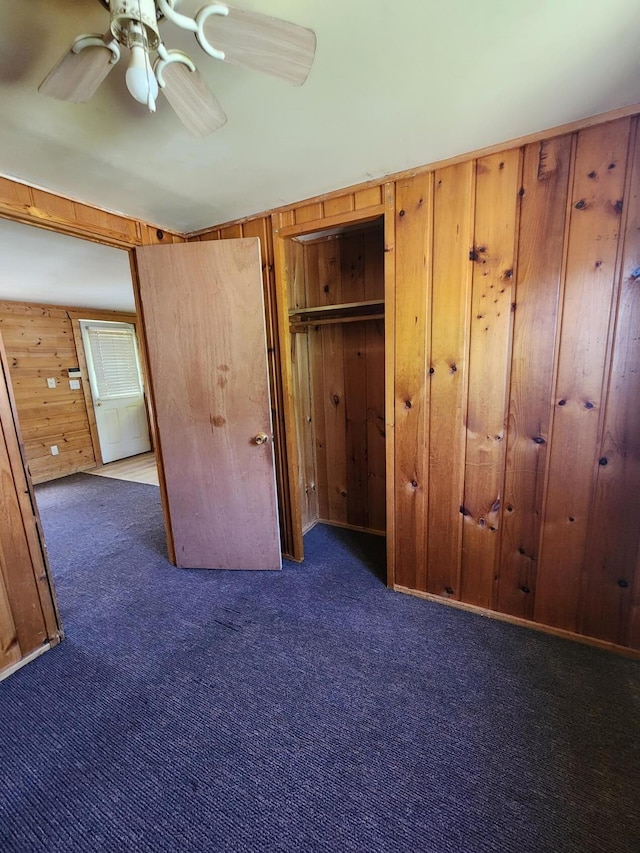 11359 Polaris St, Saint Helen, MI 48656 - unfurnished bedroom with carpet flooring, wood walls, a ceiling fan, and a closet