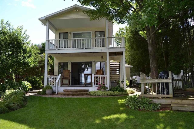 back of property with a balcony, a yard, and covered porch