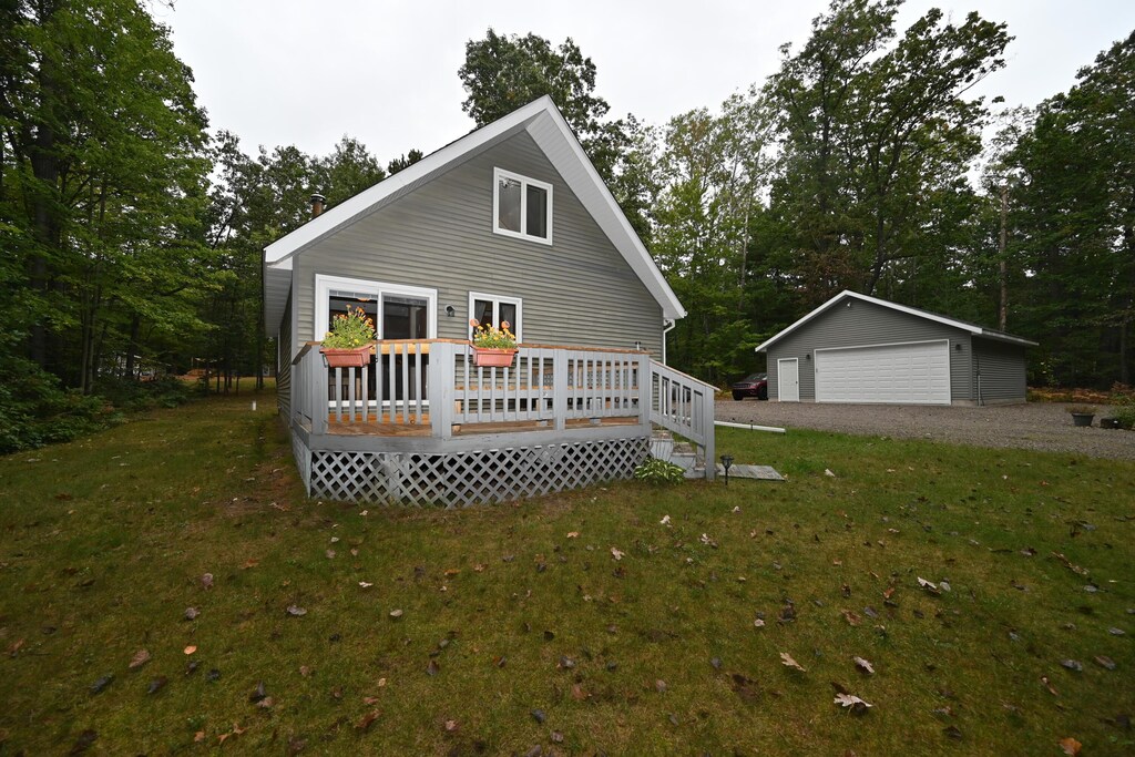 7075 W Nestel Rd, Houghton Lake, MI 48629 - exterior space featuring an outbuilding, a deck, a yard, and a detached garage