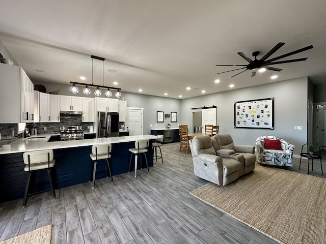 living area featuring a barn door, recessed lighting, a ceiling fan, and light wood-style floors
