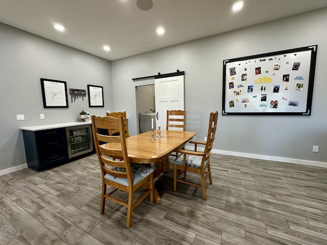 dining area with recessed lighting, a barn door, baseboards, wood finished floors, and beverage cooler