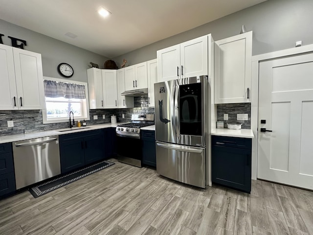 kitchen with a sink, white cabinetry, stainless steel appliances, and light countertops
