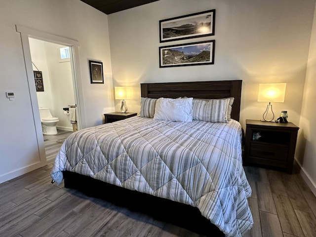 bedroom with ensuite bathroom, wood finished floors, and baseboards