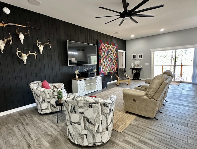 living area with recessed lighting, an accent wall, wood walls, ceiling fan, and light wood-type flooring