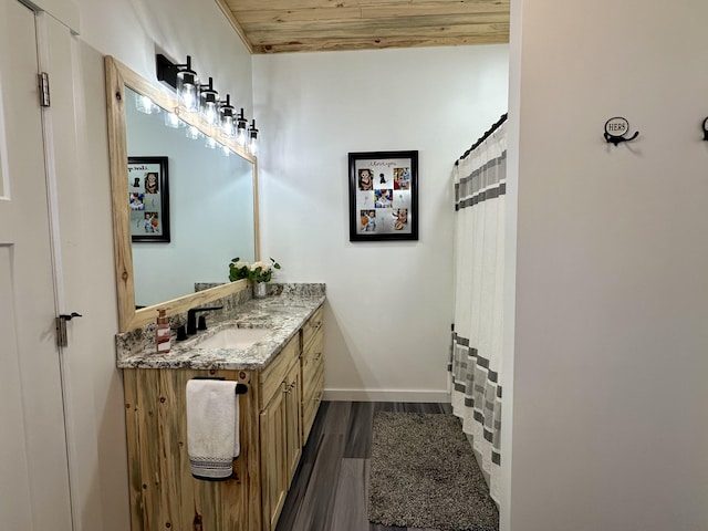 full bath with wood finished floors, vanity, and baseboards