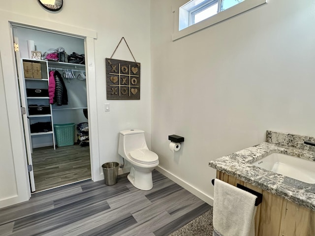 bathroom featuring wood finished floors, toilet, vanity, and baseboards
