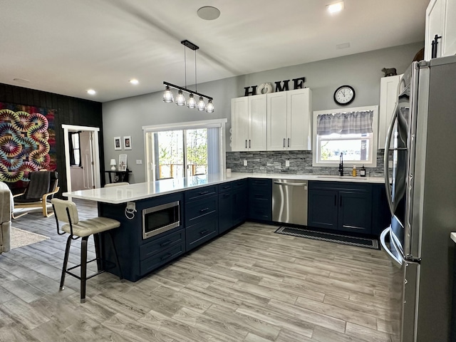 kitchen with a sink, stainless steel appliances, a breakfast bar, a peninsula, and light countertops