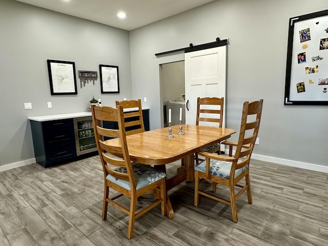 dining space featuring a barn door, recessed lighting, light wood finished floors, and baseboards