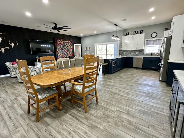 dining room featuring recessed lighting, light wood-type flooring, wooden walls, a ceiling fan, and an accent wall