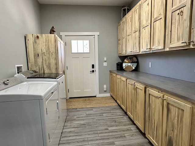washroom featuring cabinet space, light wood-style flooring, and washing machine and dryer