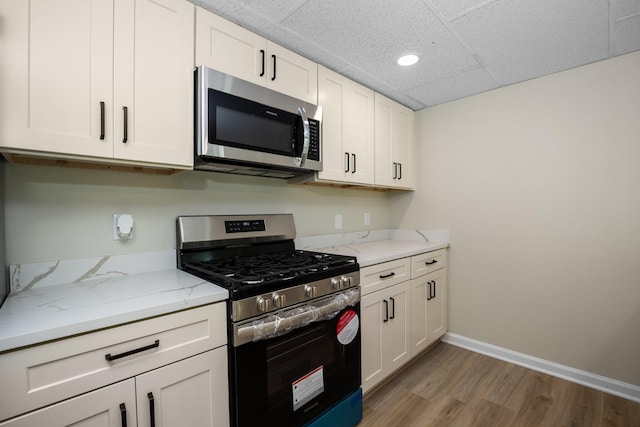 12320 E Houghton Lake Dr, Houghton Lake, MI 48629 - kitchen with stainless steel appliances, light wood finished floors, recessed lighting, light stone countertops, and white cabinets