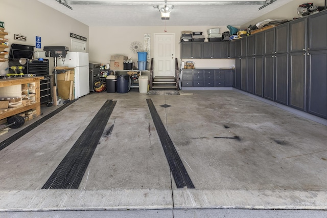 6150 Northpoint Dr, Saint Helen, MI 48656 - garage featuring a garage door opener and freestanding refrigerator
