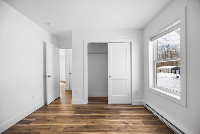 598 Gazelle St, Gaylord, MI 49735 - unfurnished bedroom with a closet, a baseboard heating unit, baseboards, and dark wood-style flooring