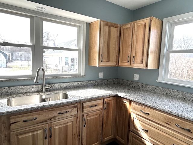 kitchen featuring a sink, plenty of natural light, and light stone counters