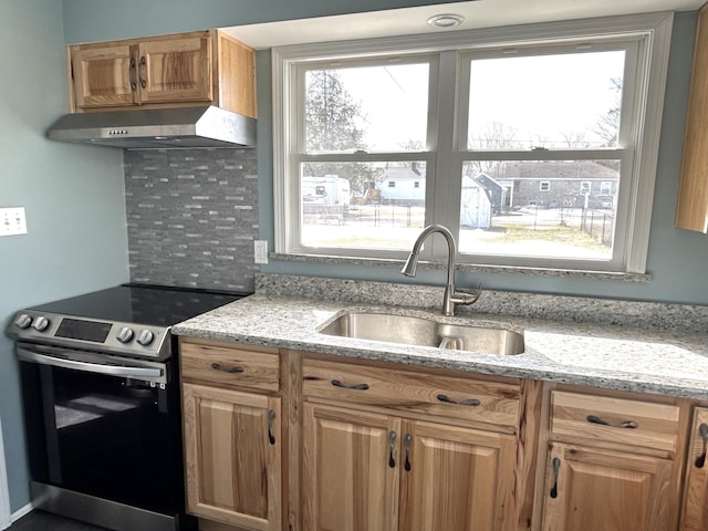 kitchen with stainless steel electric range, backsplash, a wealth of natural light, under cabinet range hood, and a sink